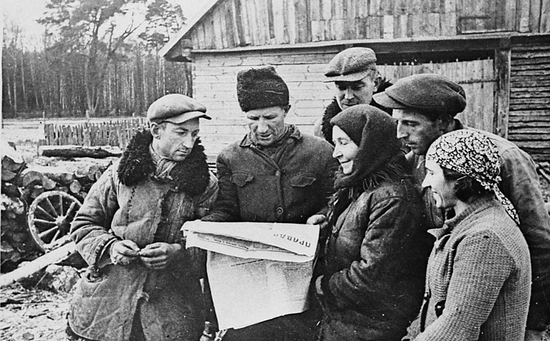 Група былых батракоў польскай памешчыцы Бійскай, якія атрымалі зямлю, чытаюць газету 