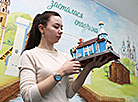 Экскурсовод Анастасия Бугвина держит в руках миниатюру храма Благовещения Пресвятой Богородицы д. Житомля