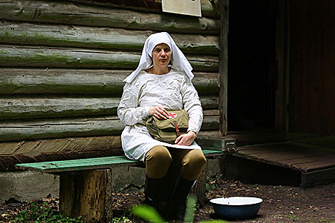 Анна Кароза в костюме партизанской медсестры у порога дома партизанской санчасти