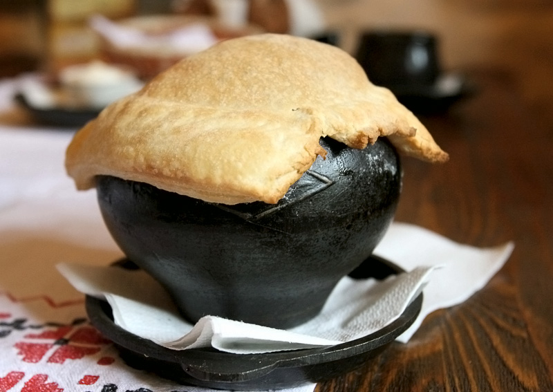 Borshch pa-tserakhouski, a red-beet soup served in a cast-iron pot covered with a pancake