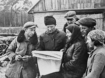 Группа бывших батраков польской помещицы Бийской, получивших землю, читают газету 